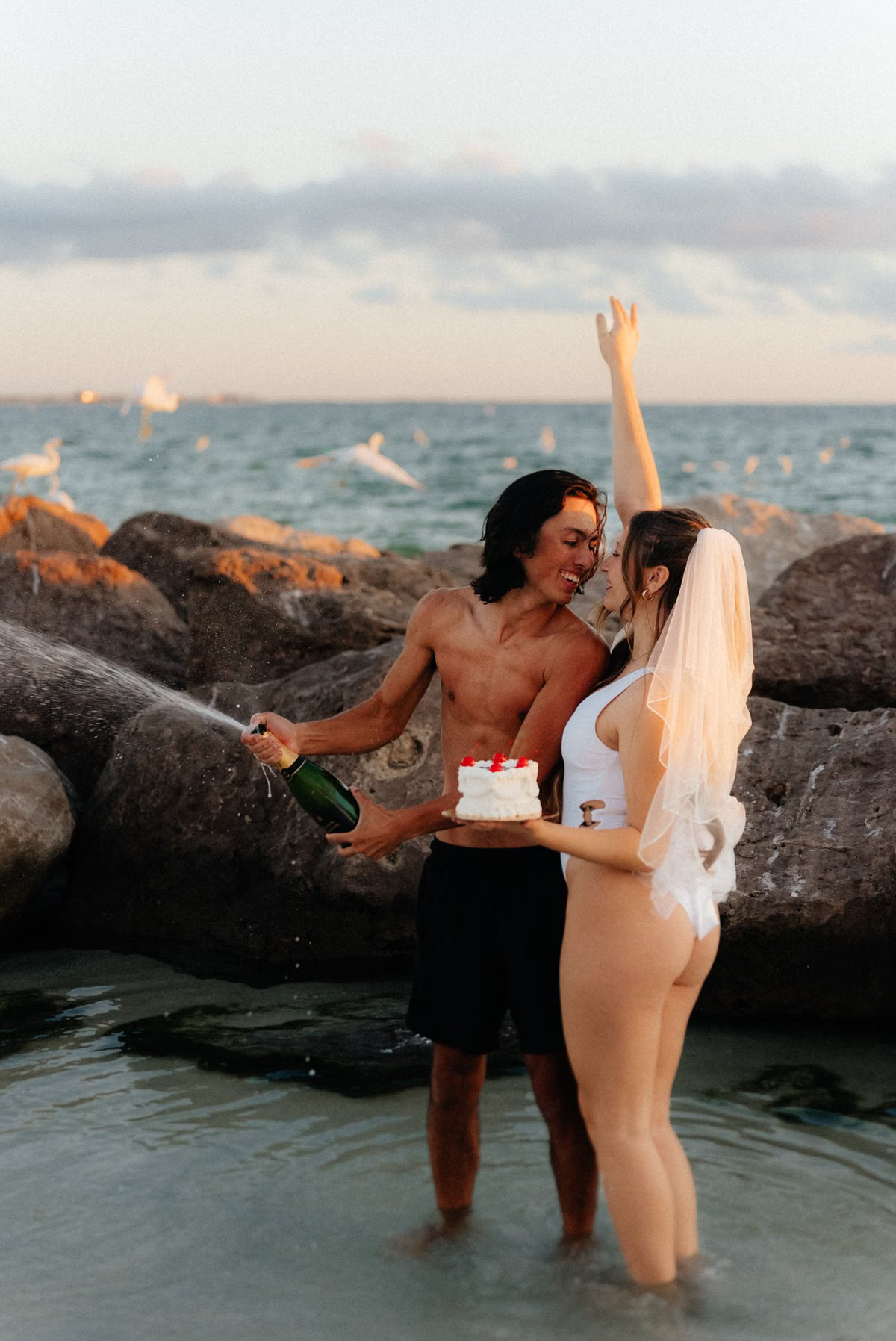 Couple celebrating their beach wedding at sunset by the sea